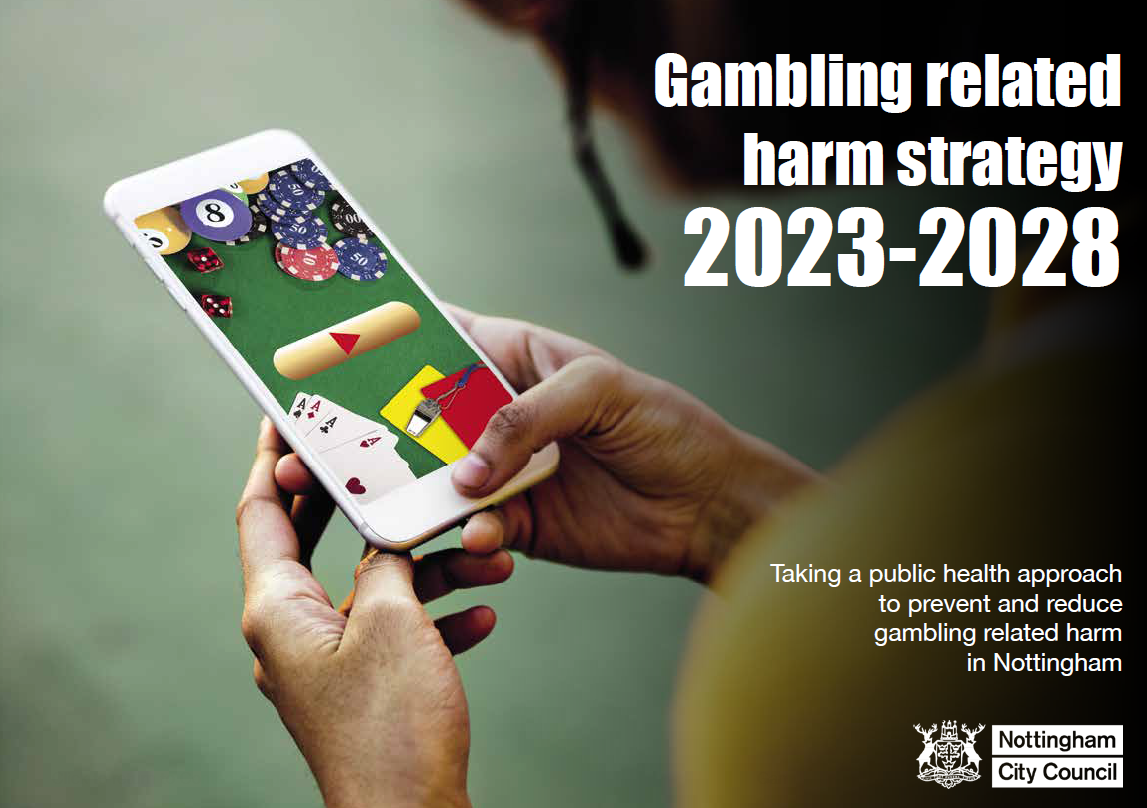 Person holding a smartphone displaying a gambling game, with text about a gambling harm strategy for 2023-2028 from Nottingham City Council.
