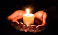 A lit candle held in the palm of someone's hands