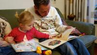 Girl and parent sat reading picture books