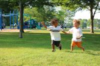 Two young children running in a park
