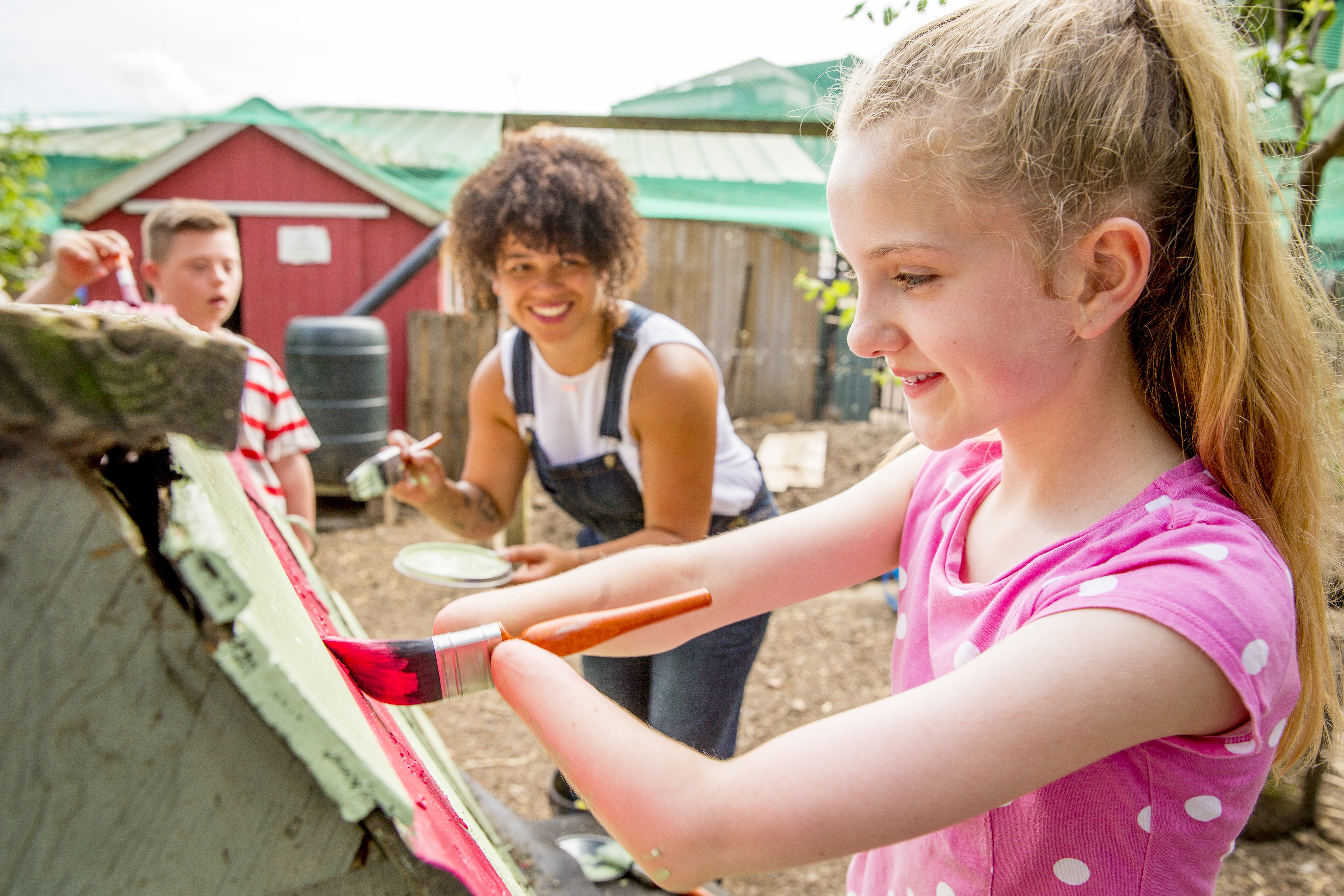 Children with disabilities painting outdoors, smiling and laughing