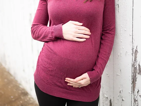 Pregnant woman with a hand on top and below her bumnp