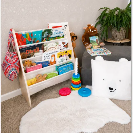Children’s reading corner with a bookshelf, rug, and toys on the floor.