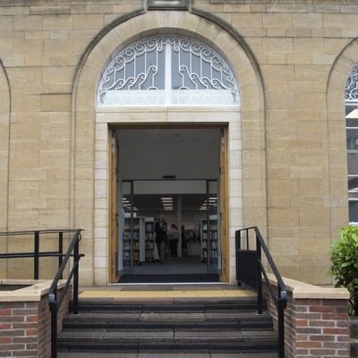 Beeston Library main entrance, three steps leading to a wide open double door under a sandstone arched frame.