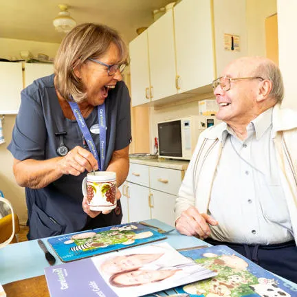Carer laughing in kitchen with older gentleman