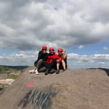 Group of young people with red climbing helmets sat on a rock