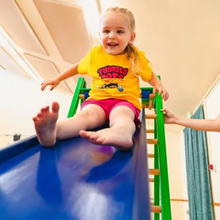 Girl being helped go down a slide