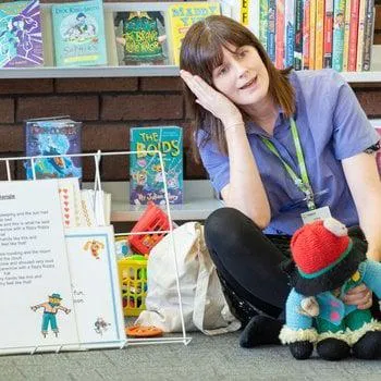 Library staff leading a rattle, rhyme and roll session with song sheets and puppets.