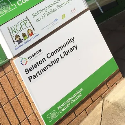 Green and white entrance sign outside Selston Library.