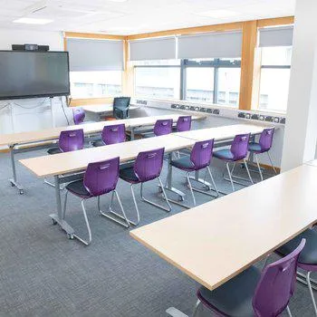 Stapleford Room 1
Bright and spacious with purple chairs and white desks. Large monitor on the far wall.