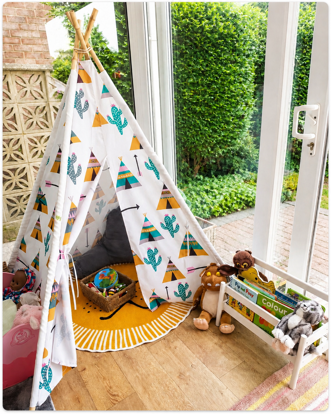 Children’s play area with a patterned teepee tent, round rug, plush toys, and a toy storage rack by large windows.